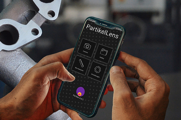Hände benutzen die PartikelLens App auf dem Handy, um Bauteile zu prüfen.
